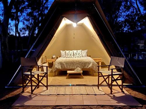 a bedroom in a tent with a bed and two chairs at Glamping at Buckland Estate in Irishtown