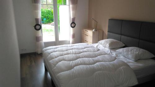 een slaapkamer met een groot wit bed en een raam bij Une grande maison familiale, à Brem sur Mer in Brem-Sur-Mer