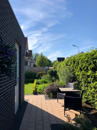 eine Terrasse mit Tisch und Bänken in einem Garten in der Unterkunft Nieboer in Vrouwenpolder