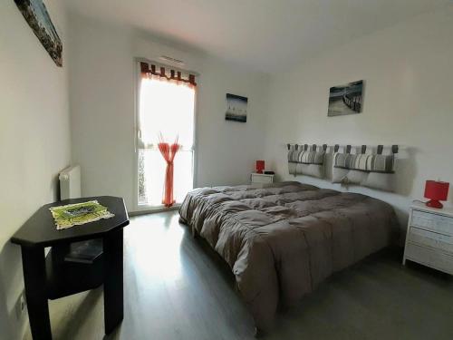 um quarto com uma cama grande e uma janela em Appartement à 150m de la grande plage de Sion em Saint-Hilaire-de-Riez