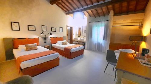 una camera con 2 letti, un tavolo e una scrivania di Il Palagione a San Gimignano