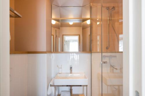 La salle de bains est pourvue d'un lavabo et d'une douche. dans l'établissement Hôtel Oratio, à Paris