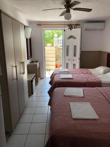 a hotel room with three beds and a window at AZALEA HOTEL in Sarti