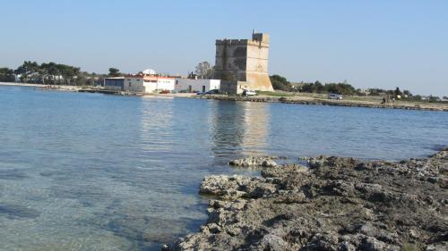 a body of water with a tower in the background at Porto Cesareo Sant'Isidoro Delizioso Trilo in Sant'Isidoro