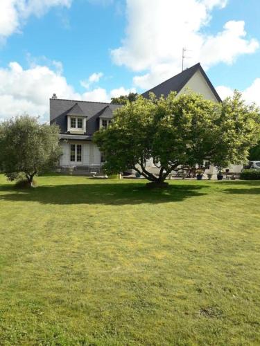 a large house with two trees in a field at Chambre sympa belle propriété in Gouesnou