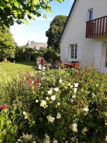 une maison blanche avec une cour fleurie dans l'établissement Chambre sympa belle propriété, à Gouesnou