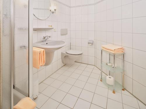 a white bathroom with a toilet and a sink at Hotel Garni Café Schacher in Oberwolfach