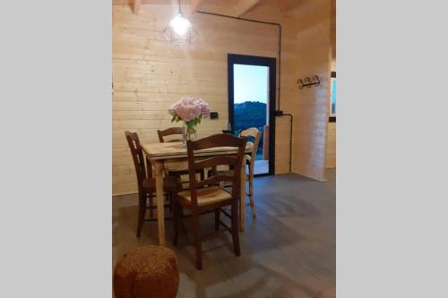 a dining room with a table with a vase of flowers on it at Eco Lodge nella natura Con Piscina privata "La Grande Quercia" in Calangianus