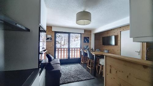 une cuisine avec un comptoir et une table avec des chaises dans l'établissement MAGNIFIQUE APPARTEMENT REFAIT à NEUF - CALME - 2 Chambres - 6 Personnes - Vue Montagne GRAND CERF 65, à Saint-Jean-dʼAulps