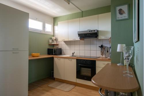 - une cuisine avec des murs verts et blancs et une table en bois dans l'établissement Appartement face mer et aux pins, à Saint-Brévin-les-Pins