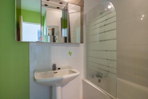 a bathroom with a sink and a shower with a mirror at Appartement face mer et aux pins in Saint-Brevin-les-Pins