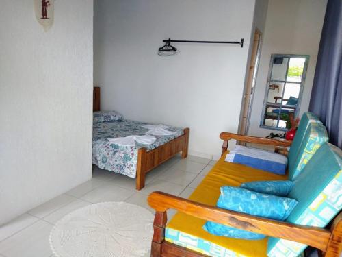 sala de estar con cama y silla en Suíte 2 com piscina e wi-fi em Caraguatatuba, en Caraguatatuba