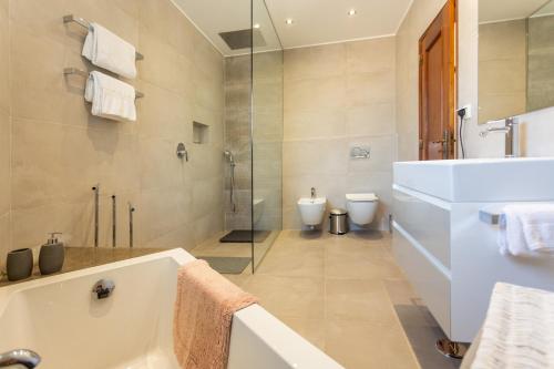 een badkamer met een bad en een douche en 2 toiletten bij Monte Lemos 29 in Luz