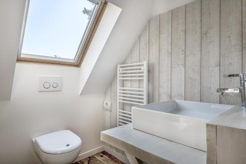 une salle de bain blanche avec des toilettes et un lavabo dans l'établissement CILAOS - Villa de charme les pieds dans l’eau, à Pornichet