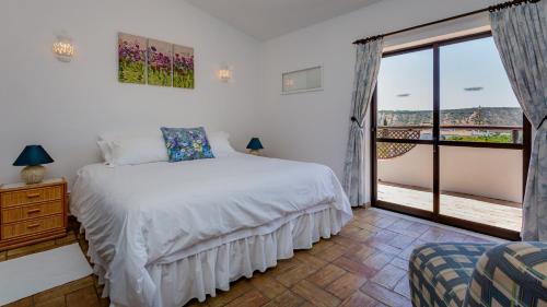 een slaapkamer met een bed en een groot raam bij Villa Strelitzia in Luz