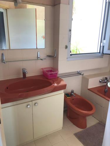 La salle de bains est pourvue d'un lavabo rouge et de toilettes. dans l'établissement Ajaccio centre ville cosy et spacieux avec climatisation, grande terrasse et vue mer, à Ajaccio