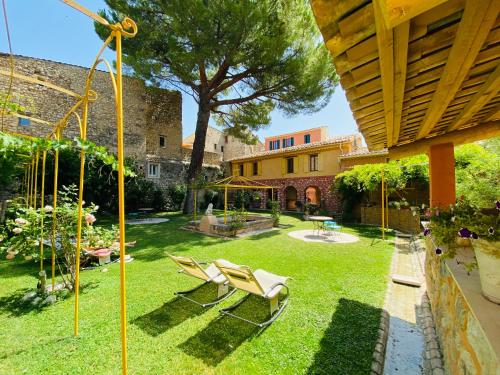 a yard with chairs and a tree and a house at Les Arcades Le Lion D'or in Buis-les-Baronnies