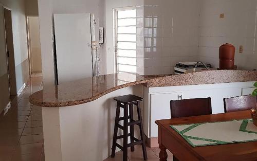 eine Küche mit einer Theke, einem Tisch und einem Stuhl in der Unterkunft Casa com churrasqueira no Centro de Caraguatatuba in Caraguatatuba