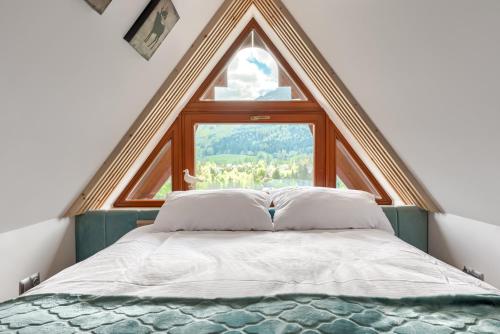a bed in a room with a large window at Tatra Resort & SPA in Kościelisko