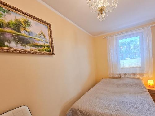 シフィノウイシチェにあるvisit baltic - Gdyńskaのベッドルーム1室(ベッド1台、窓、シャンデリア付)