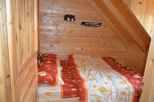 a small room with a bed in a wooden cabin at Guest House Milena in Žabljak