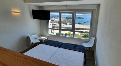 Apartamentos Costa da Morte Muxia في موتشيا: غرفة نوم بسرير ونافذة كبيرة