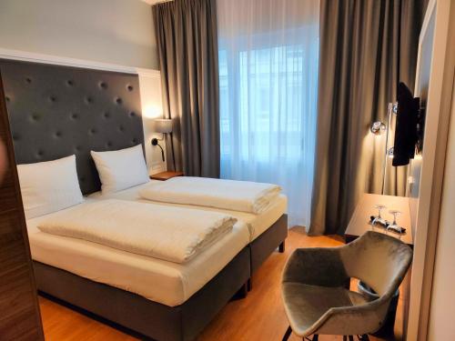 a hotel room with a bed and a chair at Signature Hotel Skarv in Elmshorn