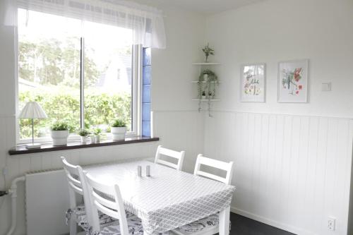 a white dining room with a white table and chairs at Kärraton Stugor Centrala Åhus in Åhus