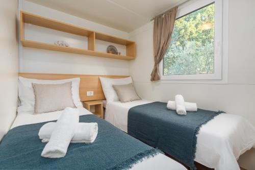 two beds in a small room with a window at Mobile Homes Banko in Bijela Uvala and Zelena laguna in Poreč