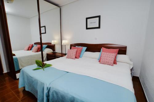 1 dormitorio con 2 camas y almohadas rosas y azules en La Senda de la Playa, en Isla