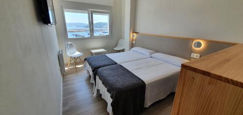 ein Hotelzimmer mit einem Bett und einem Fenster in der Unterkunft Apartamentos Costa da Morte Muxia in Muxia