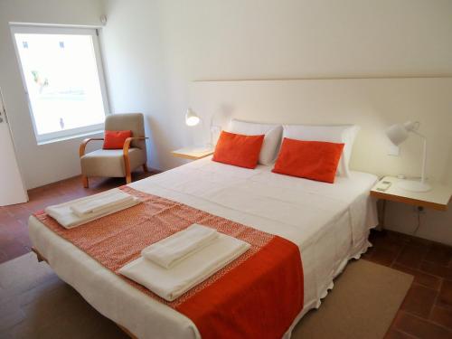 a bedroom with a large bed with orange pillows at Fine Arts Convento das Bernardas BB in Tavira