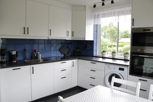 a white kitchen with white cabinets and a dishwasher at Kärraton Stugor Centrala Åhus in Åhus