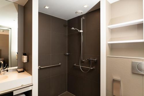 a shower with a glass door in a bathroom at Hotel de Werelt in Lunteren