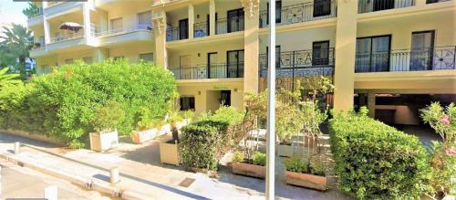 un bâtiment avec des arbres et des buissons devant lui dans l'établissement Dana centre mer 23, à Nice
