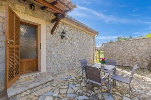 a patio with a table and chairs in front of a stone building at YourHouse Son Sant Joan in Alaró