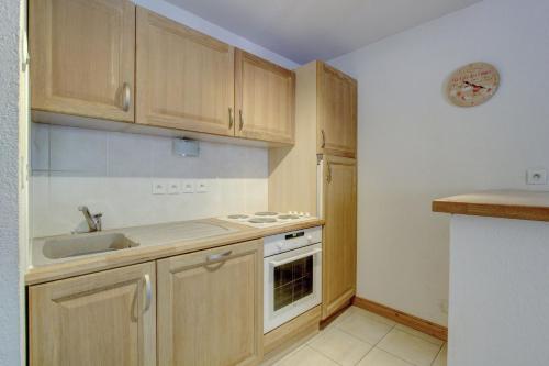 a kitchen with wooden cabinets and a sink at Slalom Apartment - Very Town Centre - Snow and Trek - Morzine in Morzine