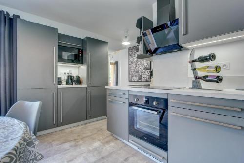 La cuisine est équipée de placards gris et d'un four avec plaques de cuisson. dans l'établissement Les Bailicîmes - Snow and Trek, à Morzine