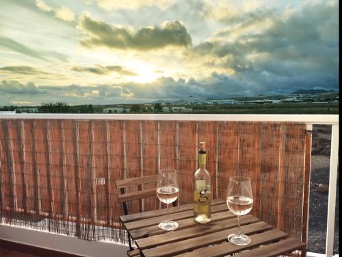 una bottiglia di vino e due bicchieri sul balcone di Ámbar a Playa Honda