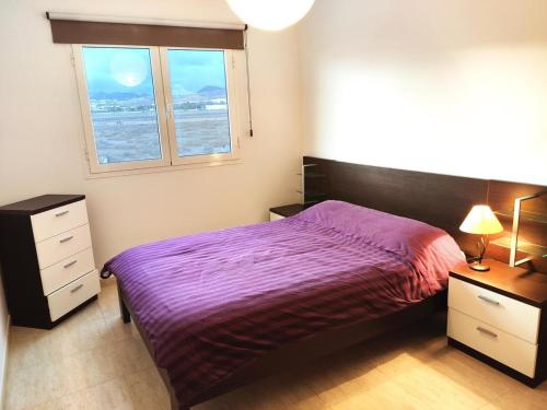 sypialnia z fioletowym łóżkiem i oknem w obiekcie Ámbar w mieście Playa Honda