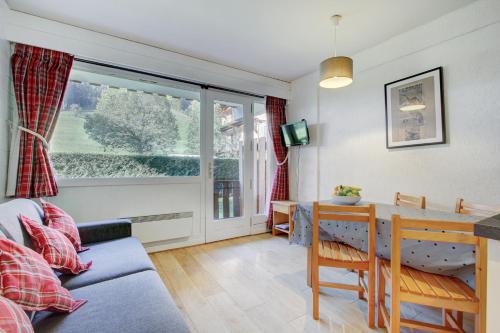 un salon avec un canapé, une table et une fenêtre dans l'établissement Atray Studio - Snow and Trek, à Morzine