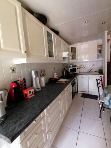 une cuisine avec des armoires blanches et un comptoir noir dans l'établissement Maisonnette bort de mer, à Frontignan