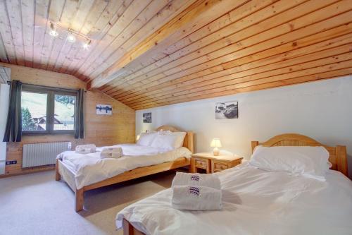 deux lits dans une chambre avec un plafond en bois dans l'établissement Bretalet - Snow and Trek, à Morzine