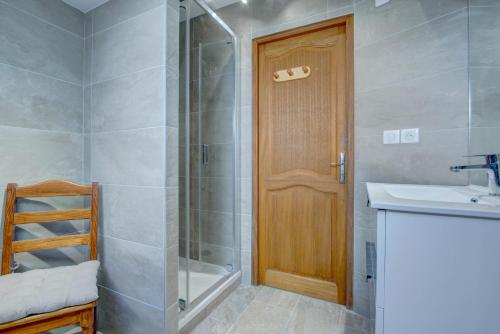 La salle de bains est pourvue d'une douche, d'un lavabo et d'une porte en bois. dans l'établissement Bretalet - Snow and Trek, à Morzine