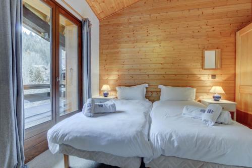 - 2 lits jumeaux dans une chambre avec des murs en bois dans l'établissement La Corniche, à Morzine