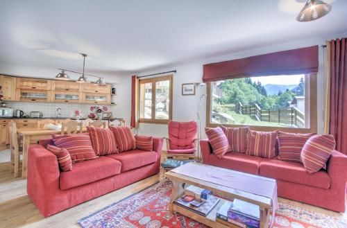 un salon avec deux canapés rouges et une cuisine dans l'établissement Chalets de Nyon - Snow and Trek, à Morzine