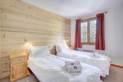 - 2 lits dans une chambre avec un mur en bois dans l'établissement Les Nants - Snow and Trek, à Morzine