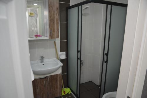 een badkamer met een wastafel en een glazen douche bij Ege Apart & Hotel in Ayvalık