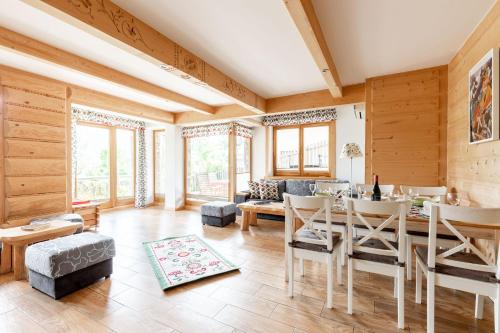 sala de estar con paredes de madera, mesa y sillas en Apartamenty Tatra View Zakopane, en Zakopane