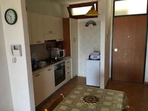 a small kitchen with a table and a clock on the wall at Porto Cesareo Sant'Isidoro Delizioso Trilo in Sant'Isidoro